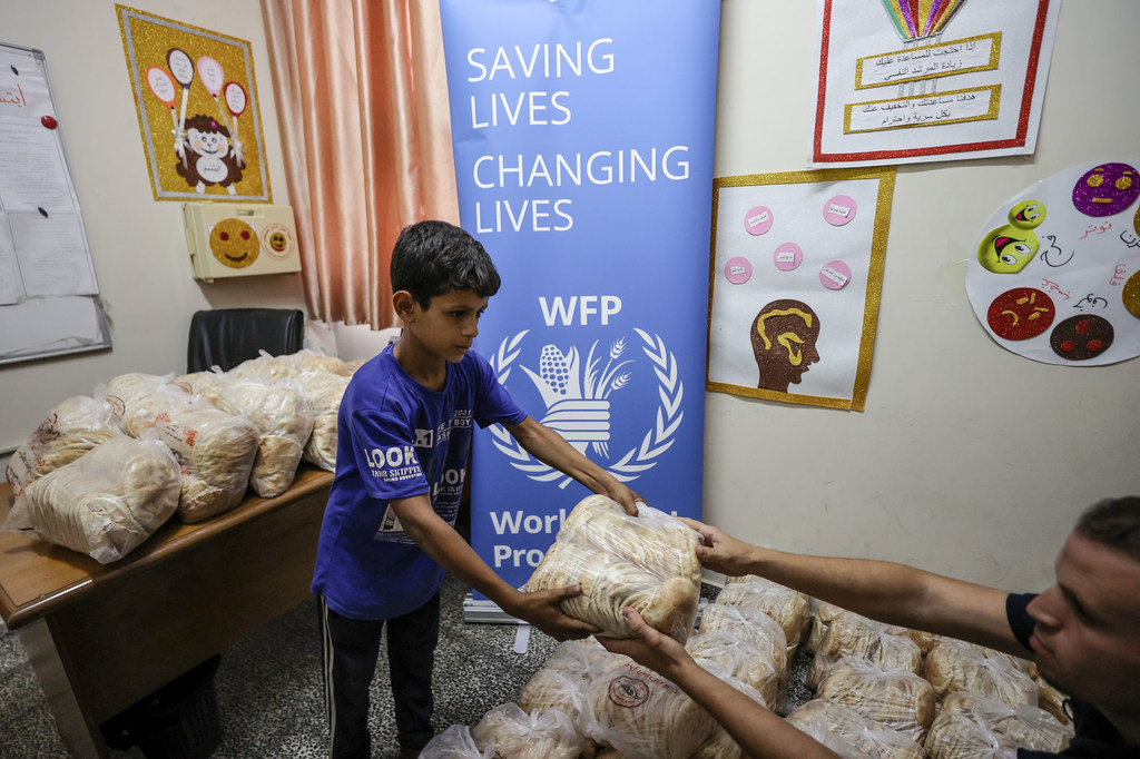 Un garçon récupère du pain auprès du PAM, dans un abri à Gaza.