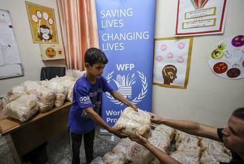 صبي يحصل على الخبز من برنامج الأغذية العالمي في ملجأ في غزة.
