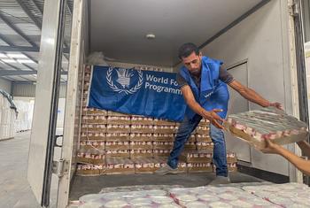 Um trabalhador descarrega alimentos prontos para consumo de um caminhão perto de Alexandria, no Egito, em preparação para entrega em Gaza