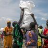 Pessoas da comunidade transportando alimentos da zona de lançamento aéreo em Rupchai, no estado de Unity, no Sudão do Sul