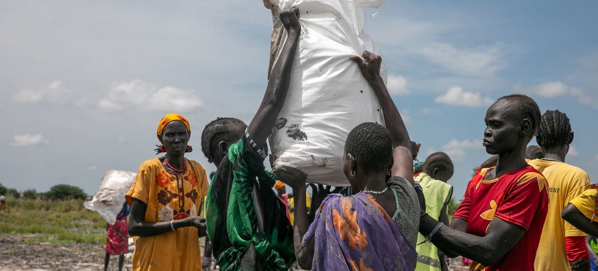 Pessoas da comunidade transportando alimentos da zona de lançamento aéreo em Rupchai, no estado de Unity, no Sudão do Sul