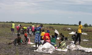La gente en Rupchai, Sudán del Sur, recoge ayuda alimentaria lanzada desde aviones.