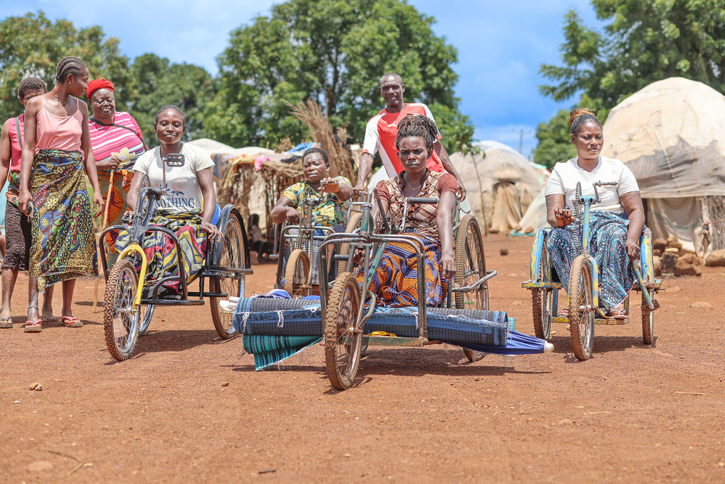 Mujeres en triciclos se abren paso por un campamento para personas desplazadas en Nigeria.