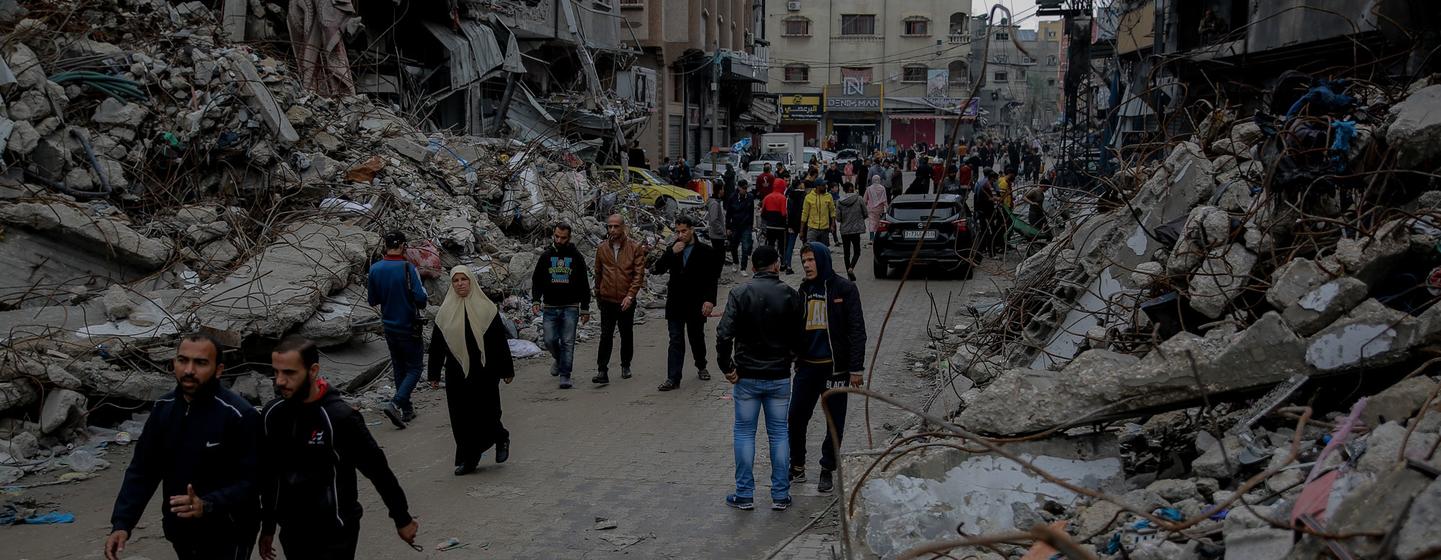在加沙地带北部，人们经过他们被摧毁的家园。