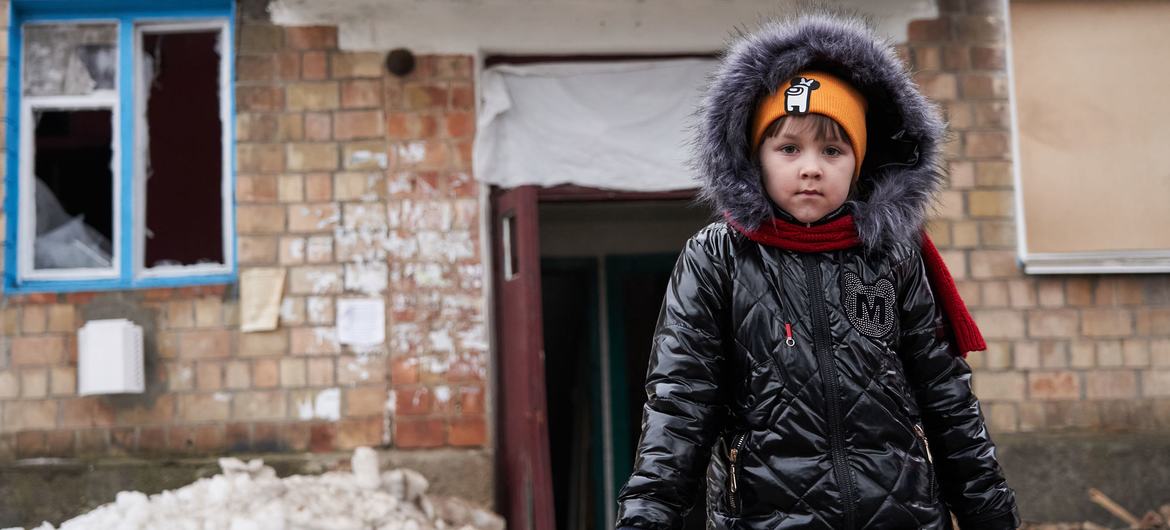 Une fillette se tient devant un bâtiment endommagé par les bombardements en Ukraine.