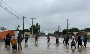 On 19 January 2026, residents walk through a flooded street in Xai Xai, Gaza province, Mozambique, following extreme rainfall caused by climate change.