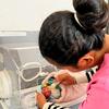 A premature baby is fed in a hospital incubator.