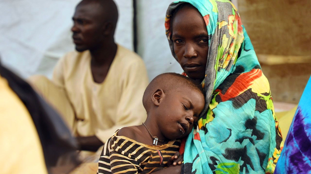Une mère ayant fui le Soudan attend dans un centre de distribution de nourriture au Tchad.