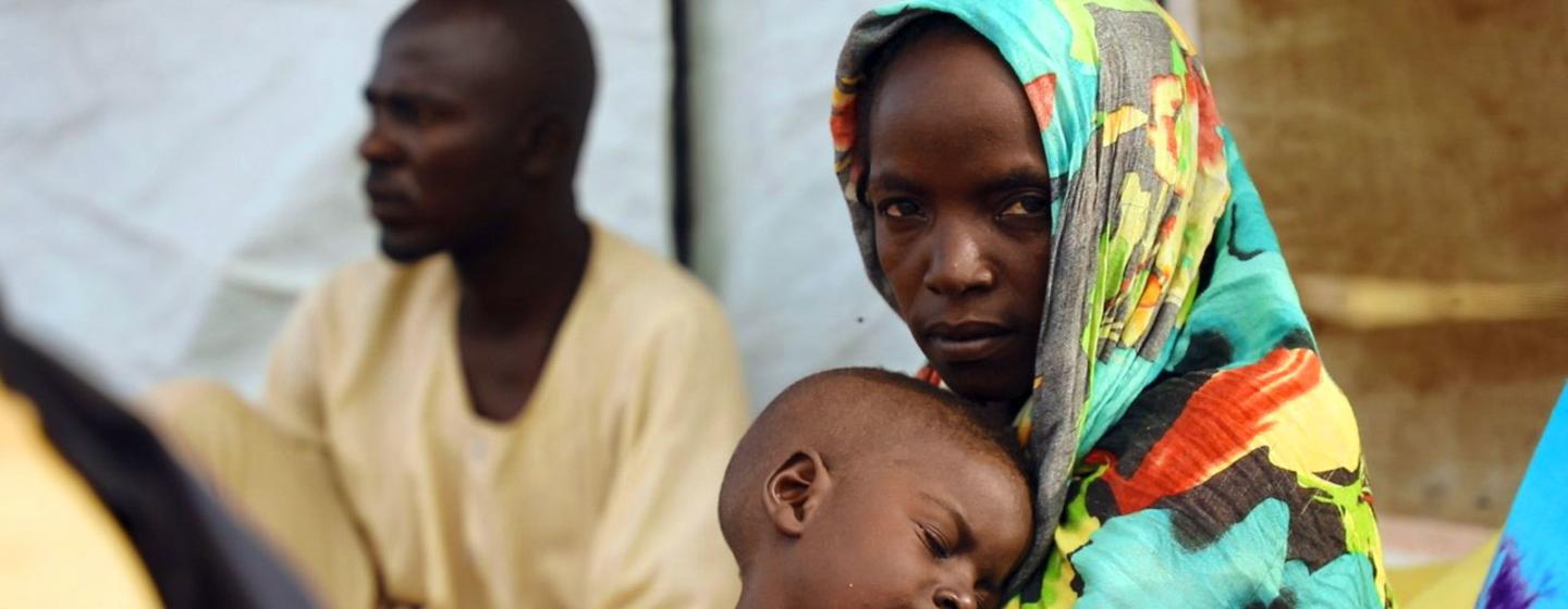 Une mère ayant fui le Soudan attend dans un centre de distribution de nourriture au Tchad.