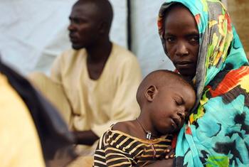 Une mère ayant fui le Soudan attend dans un centre de distribution de nourriture au Tchad.
