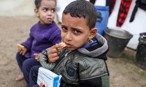 Des enfants déplacés mangent des biscuits à haute teneur énergétique dans un abri de fortune au centre de Gaza.