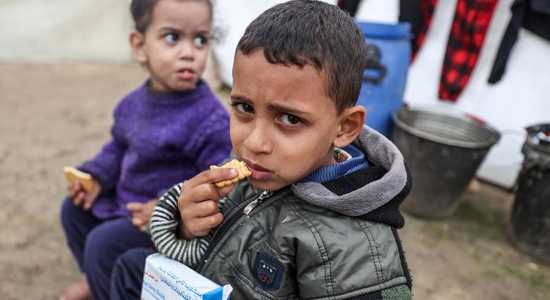 Des enfants déplacés mangent des biscuits à haute teneur énergétique dans un abri de fortune au centre de Gaza.
