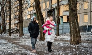 A mother and her two daughters walk past damaged buildings in Kharkiv, Ukraine.