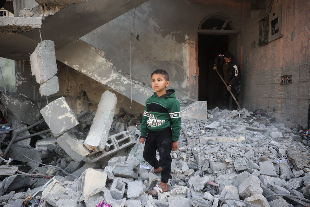 A young boy walks through the rubble of his home in Al Nusirat, Gaza.