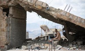 A father holds his child amid the rubble of a destroyed house in Taiz city, Yemen.