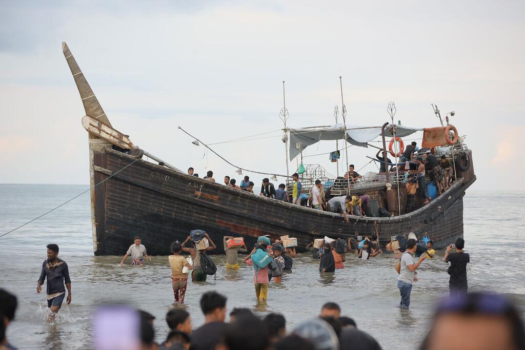 Des réfugiés rohingyas transportent leurs affaires d'un bateau en bois vers la plage d'Ulee Madon, dans le nord d'Aceh, en Indonésie.