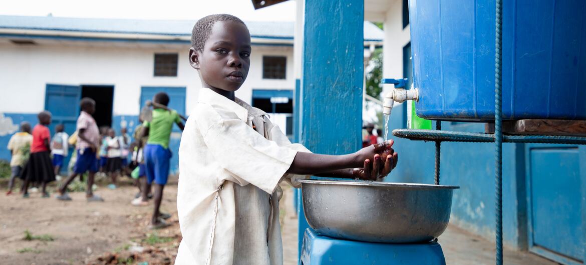 MUNGURA Claudine, une élève de 12 ans de l'école primaire de BIRINGI, se lave les mains avec de l'eau provenant d'un distributeur bleu dans son école de Biringi, dans le territoire de l'ARU, à Ituri, en République démocratique du Congo.