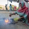 In Karachi, Pakistan, a woman burns trash to cook food causing air pollution.