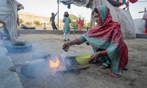 In Karachi, Pakistan, a woman burns trash to cook food causing air pollution.