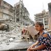 一个女孩坐在加沙被毁建筑的废墟中。