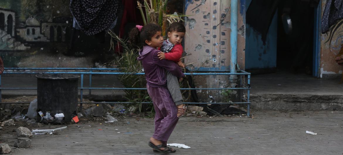 A child carries a baby through the streets of Gaza.