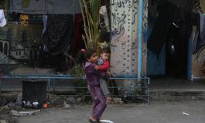 A child carries a baby through the streets of Gaza.