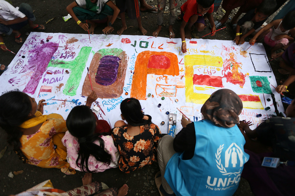 Watoto wakimbizi wa Rohingya katika kambi huko Aceh, Indonesia, wakipaka rangi bango kubwa la 'HOPE' lenye mjitolea wa UNHCR .