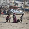 A family carries their belongings as they walk across rubble and ruin in Gaza.