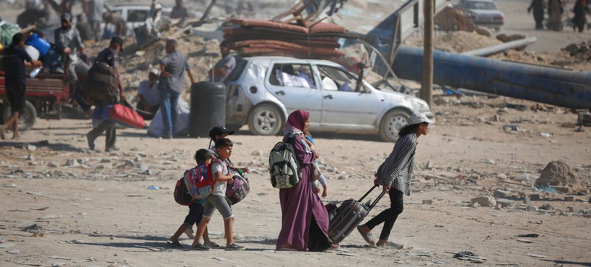 A family carries their belongings as they walk across rubble and ruin in Gaza.