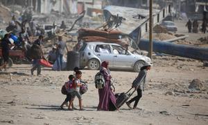 A family carries their belongings as they walk across rubble and ruin in Gaza.