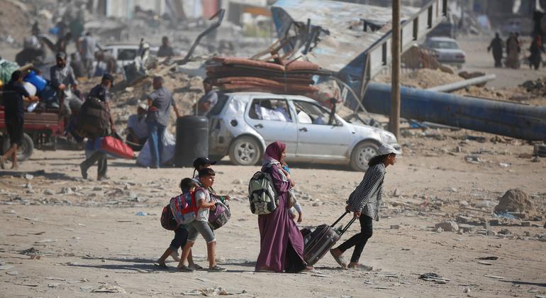 A family carries their belongings as they walk across rubble and ruin in Gaza.