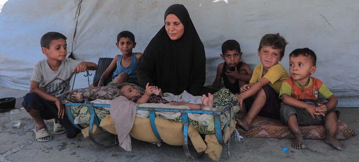 A displaced family sit in front of their tent in Gaza. A displaced family sit in front of their tent in Gaza.