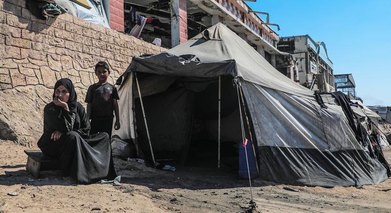 Una familia desplazada en Gaza frente a la tienda de campaña en la que se refugia.