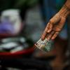 Uma mão de mulher segura uma nota de 1.000 rupias durante uma transação em um mercado na Indonésia.