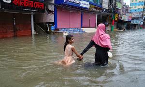 A mother guides her daughter through flood waters in Feni, Bangladesh.