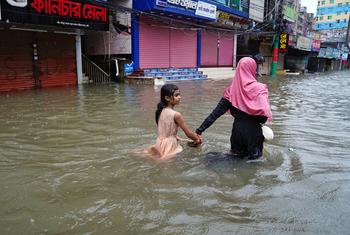A mother guides her daughter through flood waters in Feni, Bangladesh.