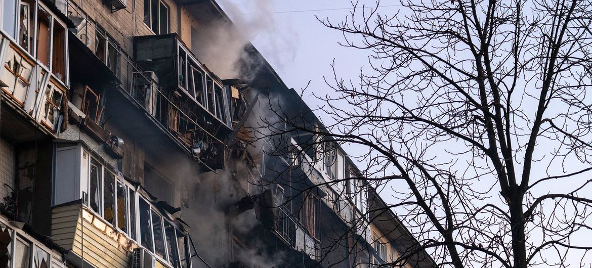 Над верхними этажами поврежденного жилого дома в Киеве поднимается дым после ночной атаки беспилотника, разрушившей несколько квартир.