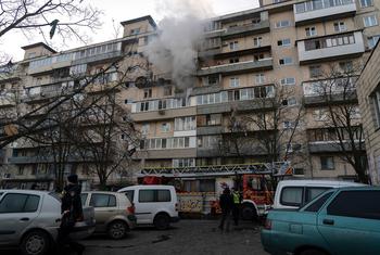 Fumaça sobe de um prédio residencial de nove andares danificado em Kiev após um ataque de drone durante a madrugada, com bombeiros e veículos de emergência no local.