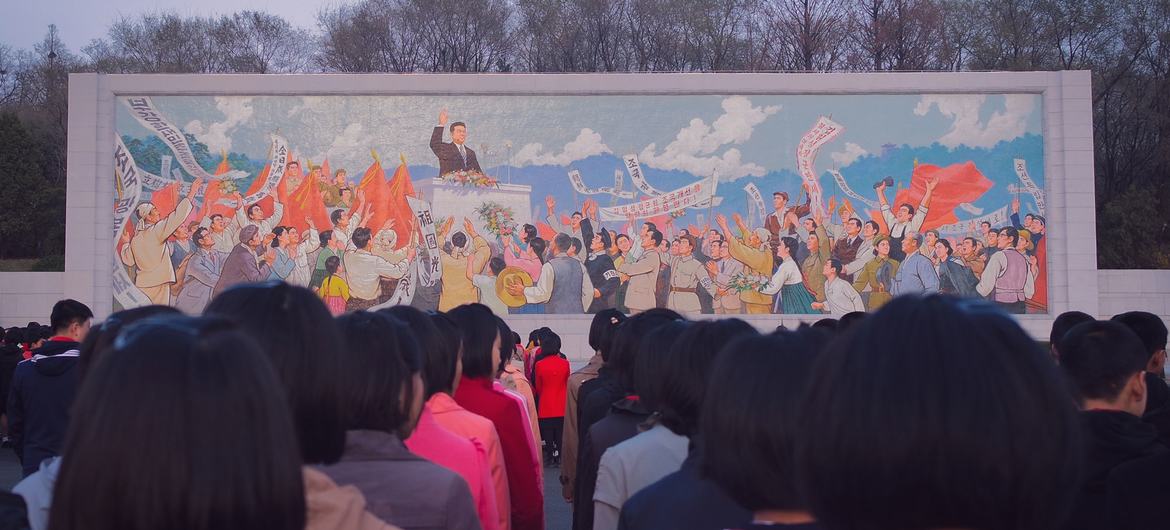 Люди стоят перед фреской в Пхеньяне, КНДР.
