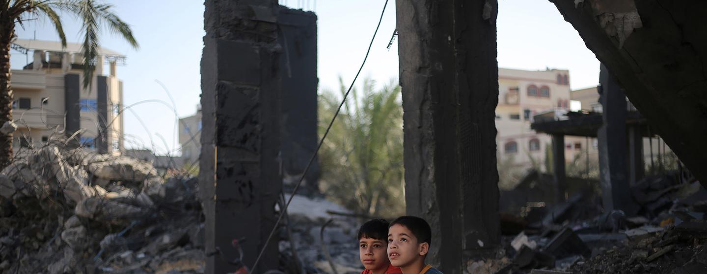 在加沙地带南部的拉法市，两名儿童坐在一片瓦砾之中，这里曾是他们的家。