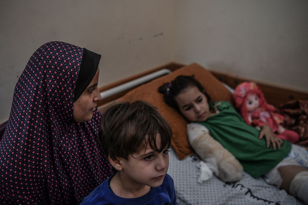 أم تعتني بابنها وابنتها اللذين أصيبا في غارة جوية على مدينة غزة.