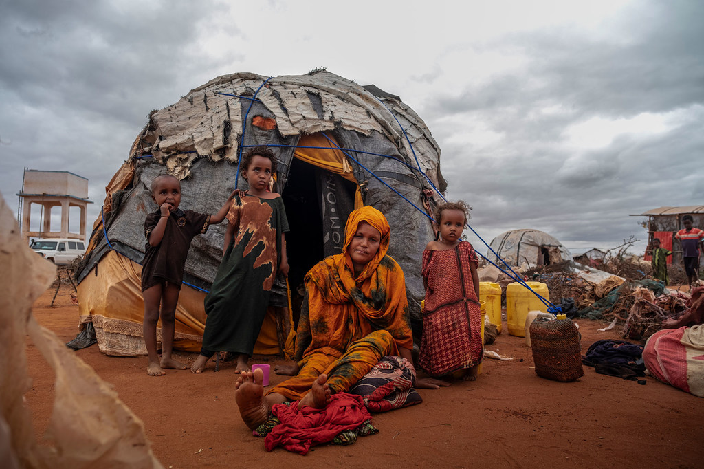 Des membres d'une famille déplacée par la sécheresse et les conflits se reposent à l'extérieur de leur tente.