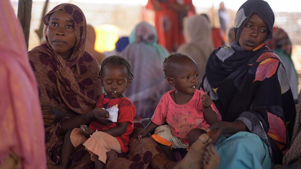 两名营养不良的儿童在苏丹北达尔富尔州塔维拉的一家卫生中心领取营养补充剂。