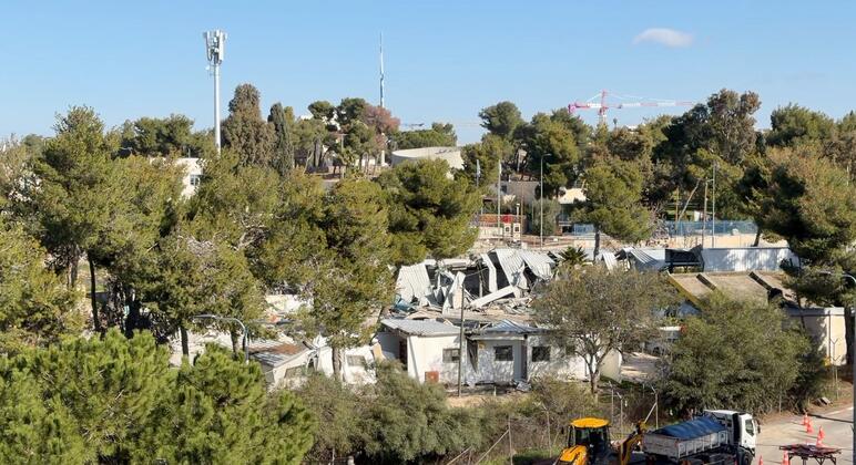 Vista aérea de la sede de la UNRWA en Jerusalén Oriental que está siendo demolida, con edificios dañados, equipos de construcción y árboles circundantes visibles.