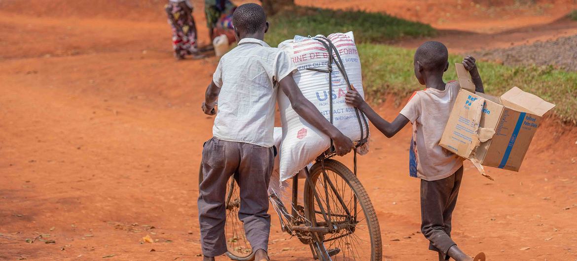 在刚果民主共和国北基伍省的贝尼，两名小男孩用自行车搬回领到的人道主义粮食援助。