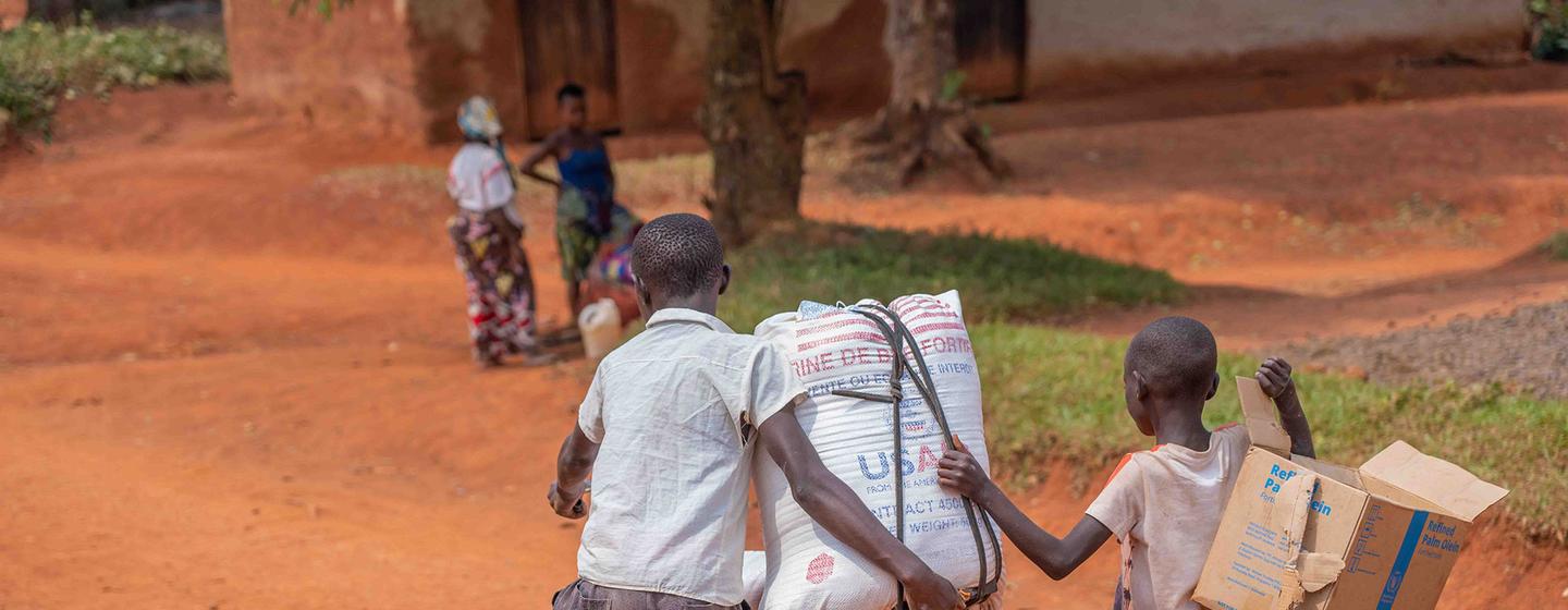 Deux jeunes garçons transportent de l'aide alimentaire à vélo à Beni, au Nord-Kivu, en RDC.