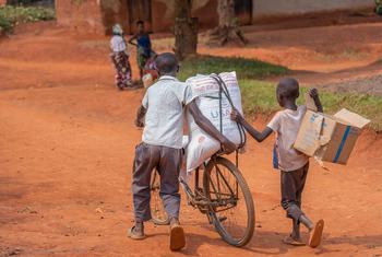 Deux jeunes garçons transportent de l'aide alimentaire à vélo à Beni, au Nord-Kivu, en RDC.