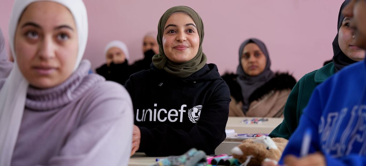 مزون المليحان سفيرة النوايا الحسنة لمنظمة اليونيسف والناشطة السورية في مجال التعليم (الوسط) تجلس على مقعد بأحد الفصول المدرسية مع عدد من الطالبات في مدرسة للفتيات في ريف دمشق، سوريا.