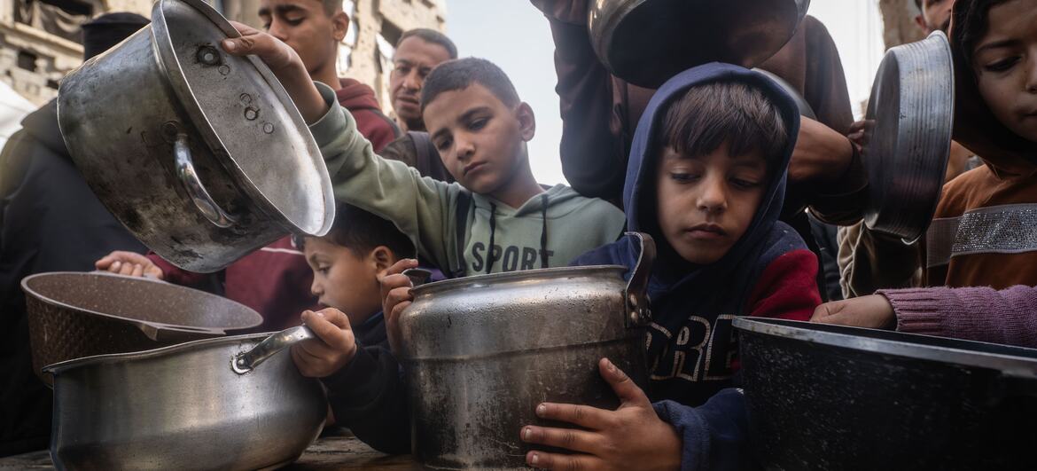 Children in Gaza receive hot meals during Ramadan from a community kitchen, highlighting the impact of displacement and humanitarian aid.