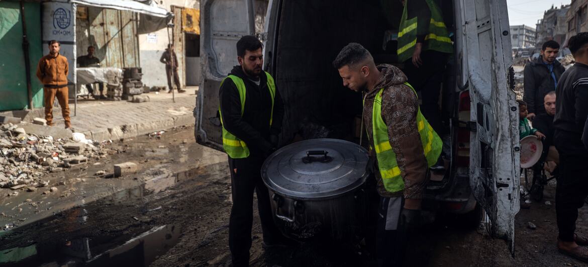تطرد المتطوعون وعاءً كبيرًا من الطعام من شاحنة في غزة، حيث يقدمون وجبات ساخنة للعائلات النازحة خلال شهر رمضان وسط الأنقاض والدمار.